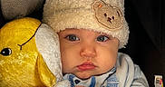 Aziel joined the competition — help win amazing prizes! baby, infant, child, portrait, face, looking_at_camera, serious_expression, winter_hat, pom_pom, beanie, blanket, plush_toy, stuffed_animal, car_seat, cozy, bundled, clothing, indoor, close_up, photography