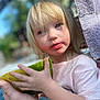 blonde_hair, blue_eyes, blurred_background, child, daylight, face, fruit, hand, holding, messy_face, nature, outdoor, person, pink_shirt, skin, snack, summer, toddler, towel, watermelon