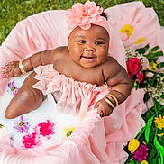 Hmonii is registered to the contest to win money with this photo: baby, infant, milk_bath, pink_clothing, flower_headband, flowers, greenery, bracelets, smiling, cute, soft_fabric, outdoor, nature, skin, water, ruffles, portrait, happy, child, sitting
