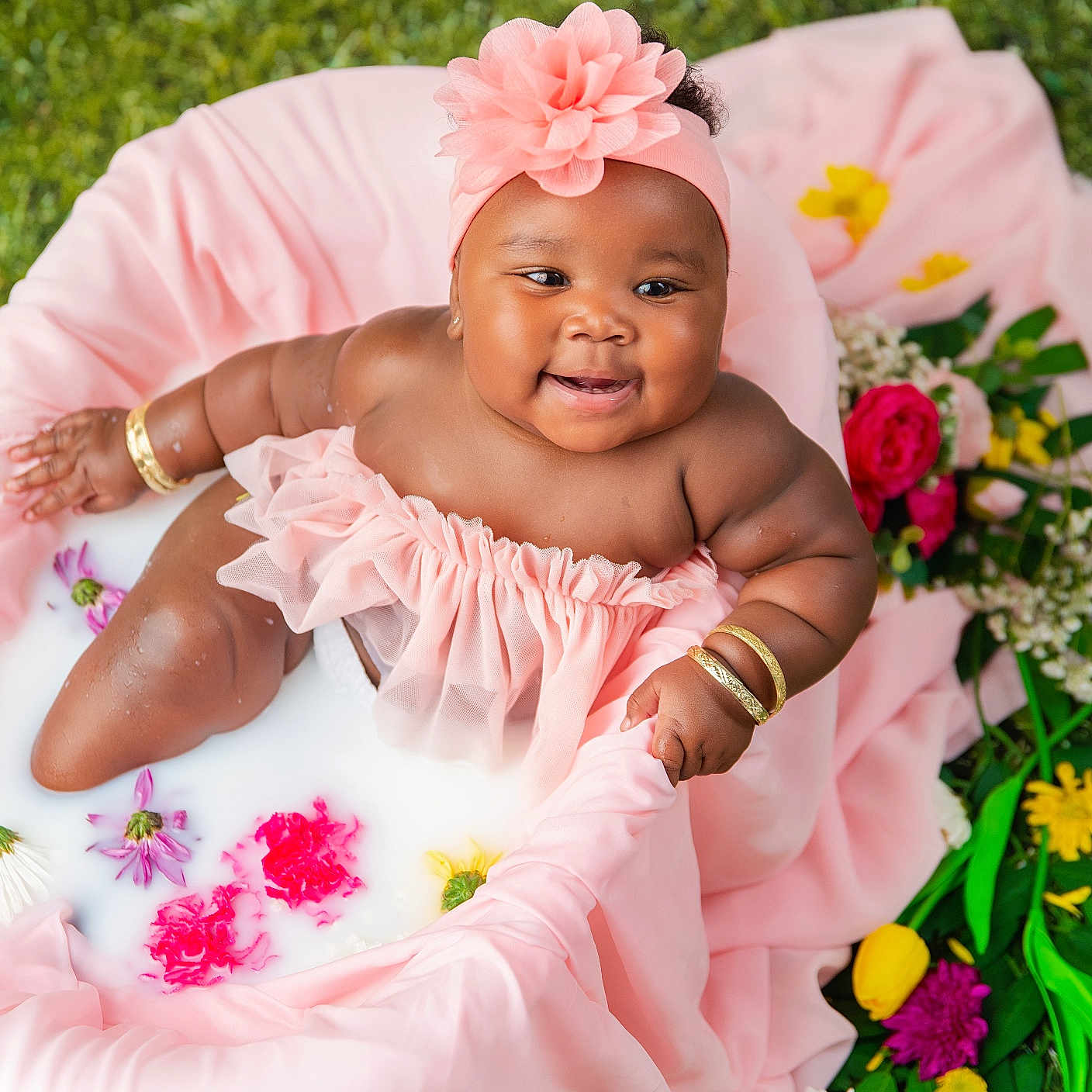 Hmonii is registered to the contest to win money with this photo: baby, infant, milk_bath, pink_clothing, flower_headband, flowers, greenery, bracelets, smiling, cute, soft_fabric, outdoor, nature, skin, water, ruffles, portrait, happy, child, sitting