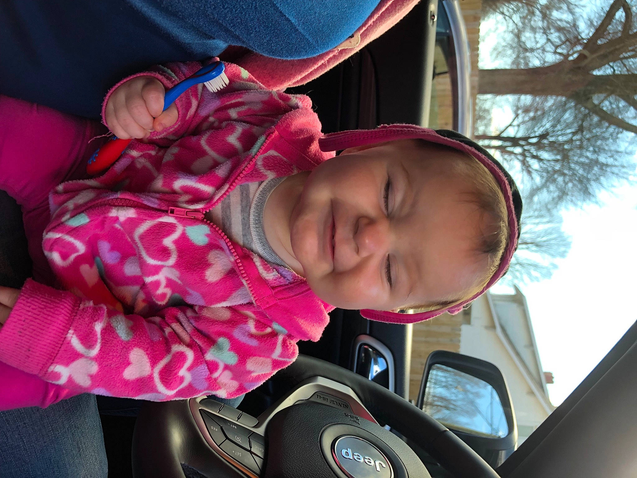 Patience is registered to the contest to win money with this photo: automotive_design, baby, car, child, eyewear, fun, happy, leisure, motor_vehicle, mouth, person, pink, plant, product, smile, steering_wheel, toddler, tree, vehicle, vehicle_door