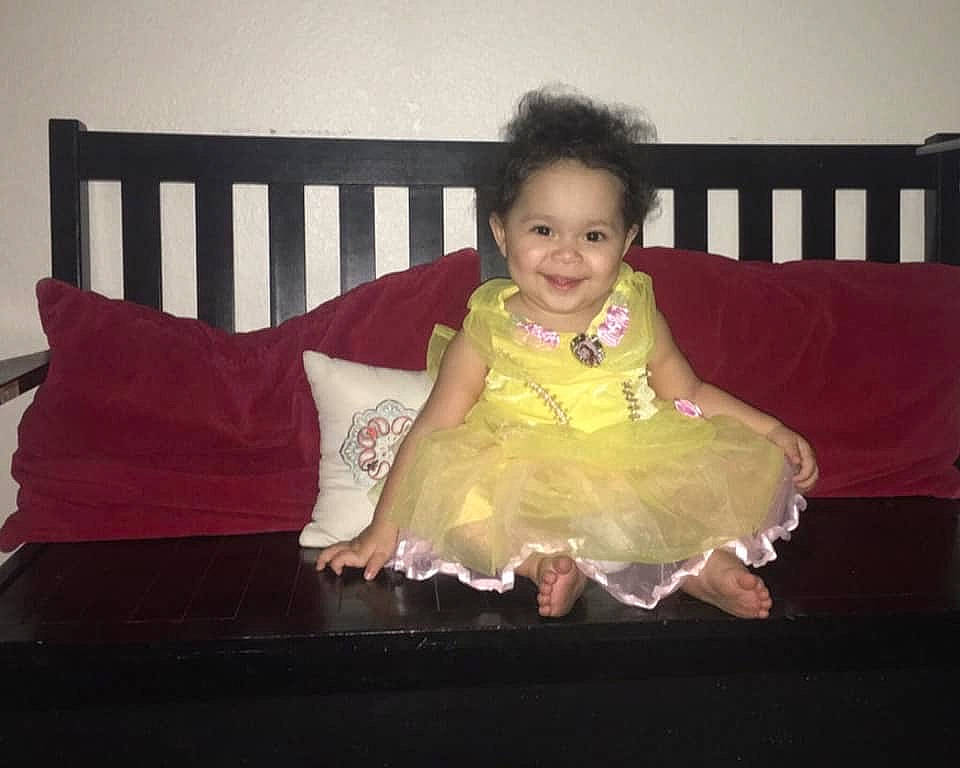 Isabella is registered to the contest to win money with this photo: baby, chair, child, costume, dress, electronic_device, eye, fun, furniture, happy, joy, person, pink, room, sitting, skin, smile, textile, toddler