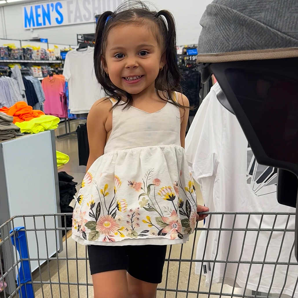 Allison is registered to the contest to win money with this photo: aisle, black_shorts, casual_clothing, child, clothing_store, cute, floral_top, girl, happy, indoor, men's_fashion, person, pigtails, portrait, retail, shopping, shopping_cart, smile, store, young