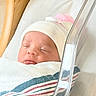 newborn, baby, sleeping, hospital, blanket, hat, pom_pom, bassinet, wood, face, infant, cozy, wrapped, peaceful, soft_lighting, healthcare, bed, child, cute, resting