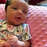 Ariannah joined the competition — help win amazing prizes! baby, infant, hand, floral_clothing, pink_cushion, red_blanket, skin, face, person, newborn, sleepy, soft_texture, resting, indoor, closeup, cute, small_hands, gentle, comfort, cozy