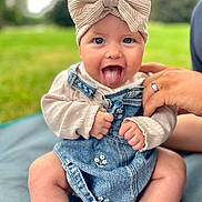 Giulia a rejoint le concours — aidez-le/la à gagner de superbes lots ! baby, child, tongue_out, headband, bow, denim_dress, sweater, hand, outdoor, grass, blanket, cute, smiling, happy, infant, person, portrait, sitting, nature, playful