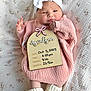 Ayvalynn Snuggs is registered to the contest to win money with this photo: baby, infant, headband, bow, pink_sweater, knitted, white_booties, blanket, patterned_blanket, newborn, portrait, lying_down, cute, soft_lighting, wooden_sign, birth_details, hand, face, feet, cozy