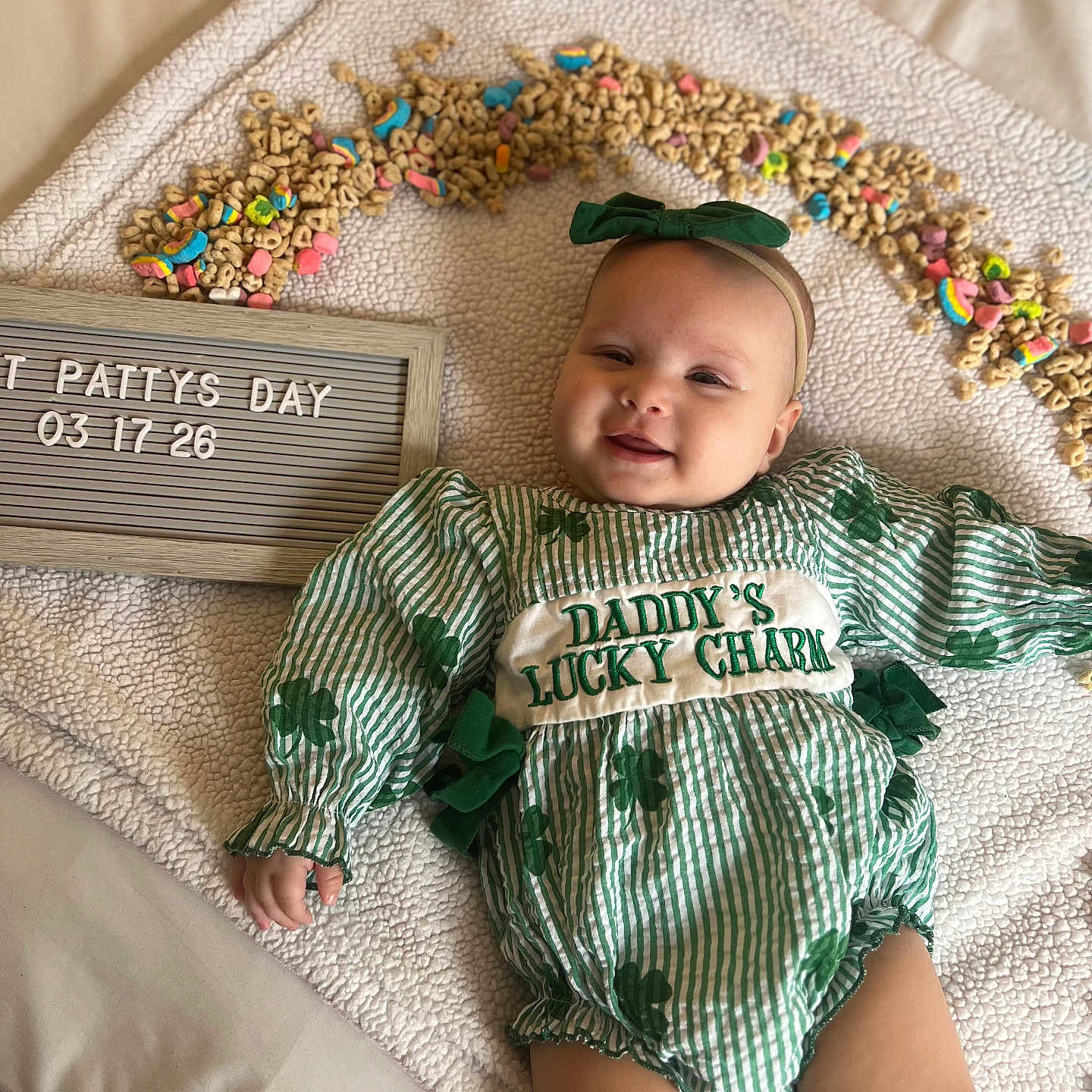 Ayvalynn Snuggs joined the competition — help win amazing prizes! baby, blanket, celebration, cereal, cheerios, child, cute, face, green_bow, green_clothing, headband, holiday_theme, indoors, infant, letter_board, lying_down, portrait, shamrocks, smiling, st_patricks_day