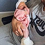 Ayvalynn Snuggs is registered to the contest to win money with this photo: newborn, baby, infant, sleeping, knitted_clothing, white_booties, headband, adult_hand, grey_shirt, nike_logo, indoor, blue_wall, seated, closeup, peaceful, portrait, person, human, soft_lighting, casual