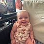 baby, smiling, infant, sitting, indoor, couch, clothing, leaf_pattern, happy, cheeks, person, cute, cushion, furniture, expression, child, pattern, seat, head, skin