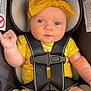 baby, infant, car_seat, yellow_bow, yellow_outfit, heart_pattern, blue_eyes, child, safety_harness, seatbelt, cute, portrait, infant_girl, car_interior, child_safety, closeup, pink_skin, hand_gesture, expression, newborn
