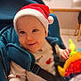 baby, blue_car_seat, child, clothing, cute, face, festive, hand, happy, holiday, indoor, infant, person, plush_toy, portrait, red_hat, santa_hat, seatbelt, smile, toy