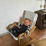 Marley a rejoint le concours — aidez-le/la à gagner de superbes lots ! baby, black_pants, carpet, casual, chair, child, cozy, cute, floor_tiles, home_interior, indoor, modern_chair, person, relaxed, shoes, smiling, striped_sweater, toddler, wooden_furniture, young_child