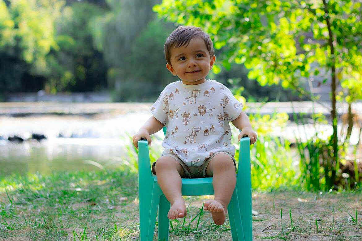 Léo participe au concours pour gagner de l'argent avec cette photo : toddler, child, smiling, outdoor, greenery, grass, sunlight, chair, casual_clothing, nature, happy, portrait, baby, shorts, summer, daylight, tree, park, playful, cute