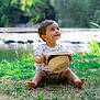 Léo participe au concours pour gagner de l'argent avec cette photo : toddler, child, grass, hat, outdoor, nature, water, smile, happy, greenery, sunlight, summer, sitting, barefoot, cute, young, casual_clothing, daytime, playful, portrait