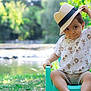 Léo a rejoint le concours — aidez-le/la à gagner de superbes lots ! baby, casual_clothing, chair, child, cute, grass, greenery, happy, hat, nature, outdoor, playful, portrait, river, sitting, smile, straw_hat, summer, sunlight, toddler