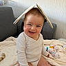baby, child, smiling, happy, book, headwear, toy, indoor, blanket, couch, furniture, cute, infant, playful, person, portrait, sitting, clothing, home, light