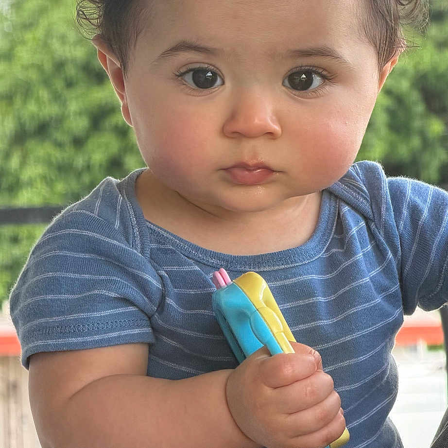 Jan Lukas joined the competition — help win amazing prizes! baby, child, toddler, portrait, face, eyes, hair, smiling, outdoor, daylight, toy, holding, blue_shirt, striped_clothing, sitting, close_up, person, nature, greenery, photography