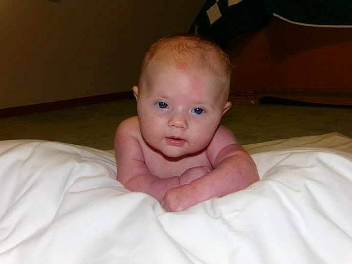 Raeleigh is registered to the contest to win money with this photo: arm, baby, baby_toddler_clothing, cheek, chest, comfort, eye, face, flooring, foot, gesture, hair, happy, head, linens, nail, person, smile, thumb, toddler