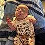 Jack is registered to the contest to win money with this photo: baby, infant, tongue_out, clothing, shirt, pants, patterned_pants, blanket, striped_blanket, indoor, cute, humor, playful, person, child, young_child, face, hand, sitting, cozy