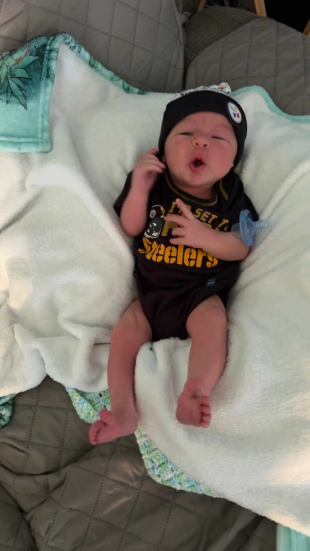 Jack is registered to the contest to win money with this photo: baby, infant, blanket, clothing, pacifier, beanie, face, expression, person, sleepwear, foot, hand, couch, quilt, soft, cute, indoors, resting, sportswear, newborn