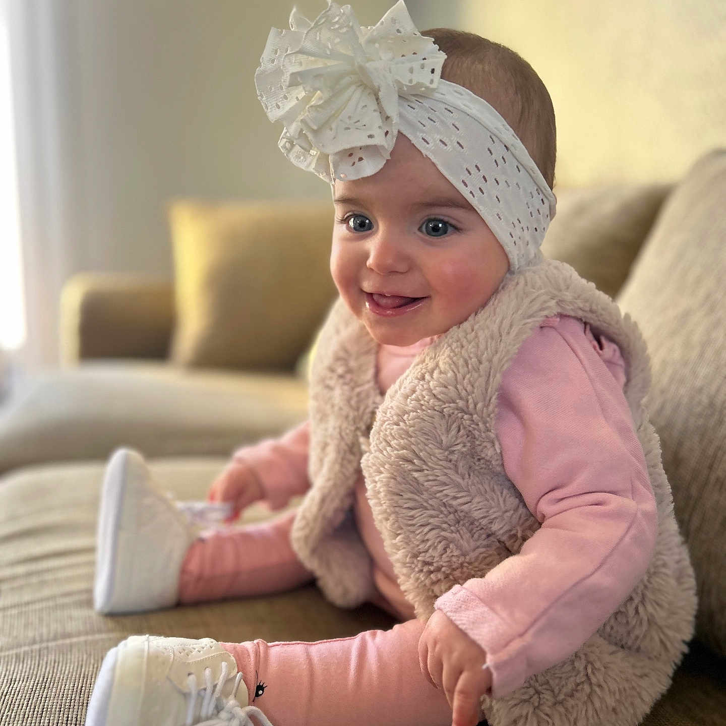 Seyanah a rejoint le concours — aidez-le/la à gagner de superbes lots ! baby, child, smiling, headband, bow, pink_clothing, furry_vest, sneakers, couch, indoor, happy, portrait, seated, cute, infant, living_room, soft_lighting, cozy, fashion, toddler