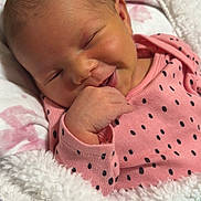 Kaiya is registered to the contest to win money with this photo: baby, newborn, smiling, blanket, pink_clothing, polka_dot, hand, face, pacifier, cozy, infant, cute, sleepy, resting, soft_texture, indoors, child, person, head, wrapped