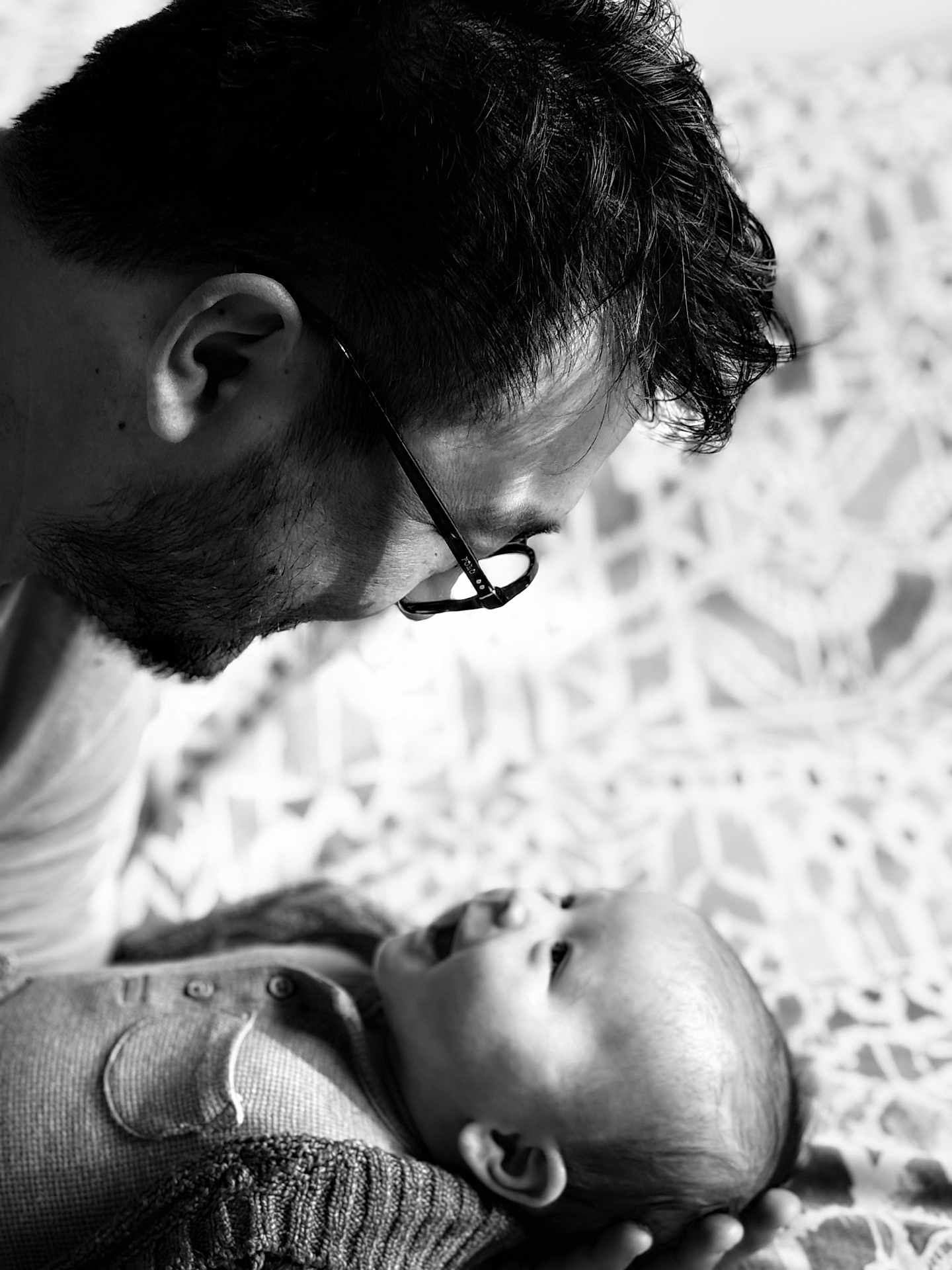 Tobyas participe au concours pour gagner de l'argent avec cette photo : baby, man, glasses, black_and_white, portrait, smile, face, love, father, child, tender, closeup, head, happy, interaction, pattern, blanket, clothing, person, family