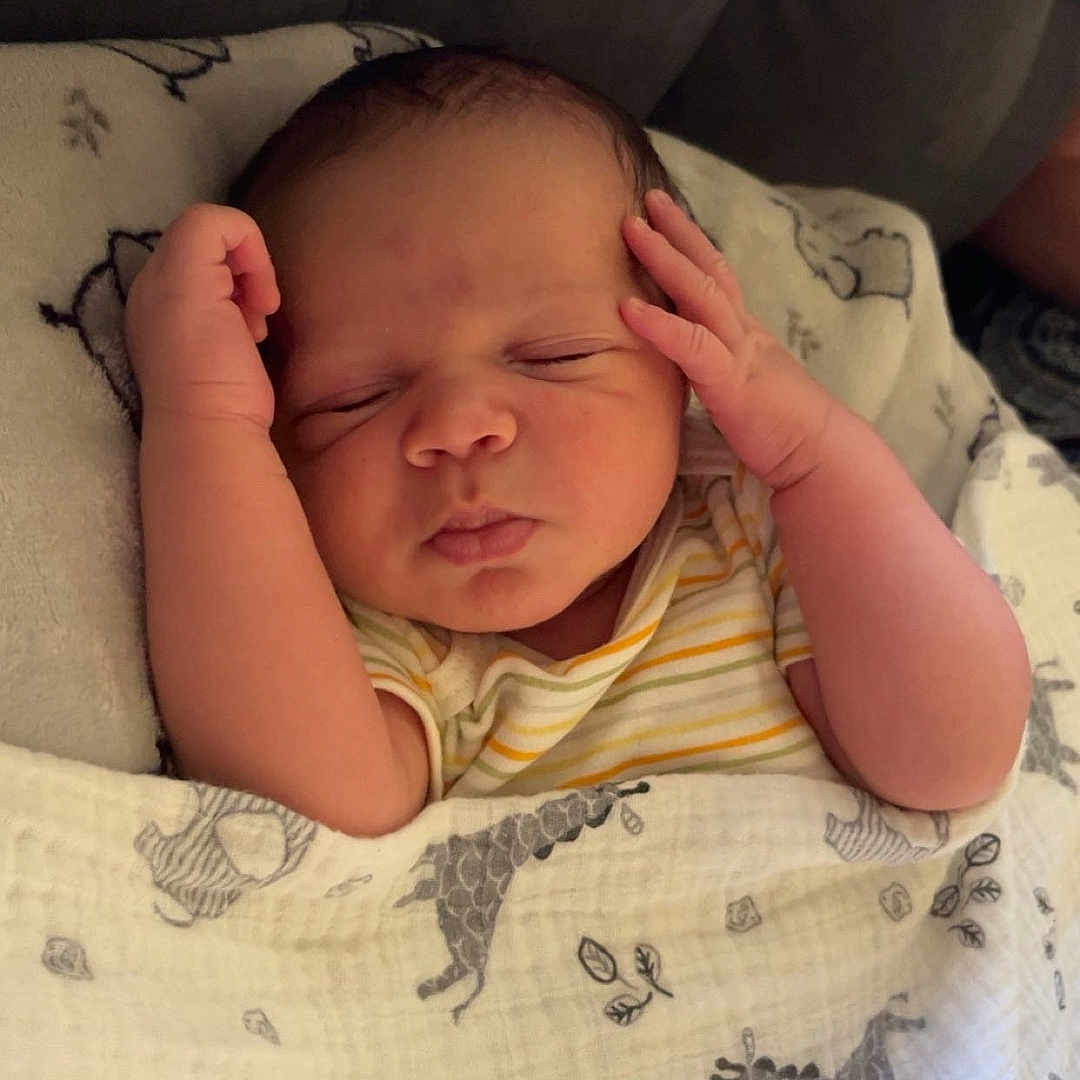 Malachi is registered to the contest to win money with this photo: animal_print, baby, blanket, child, couch, cozy, cute, face, hands, indoors, infant, newborn, peaceful, portrait, relaxing, resting, sleeping, soft, striped_clothing, wrapped