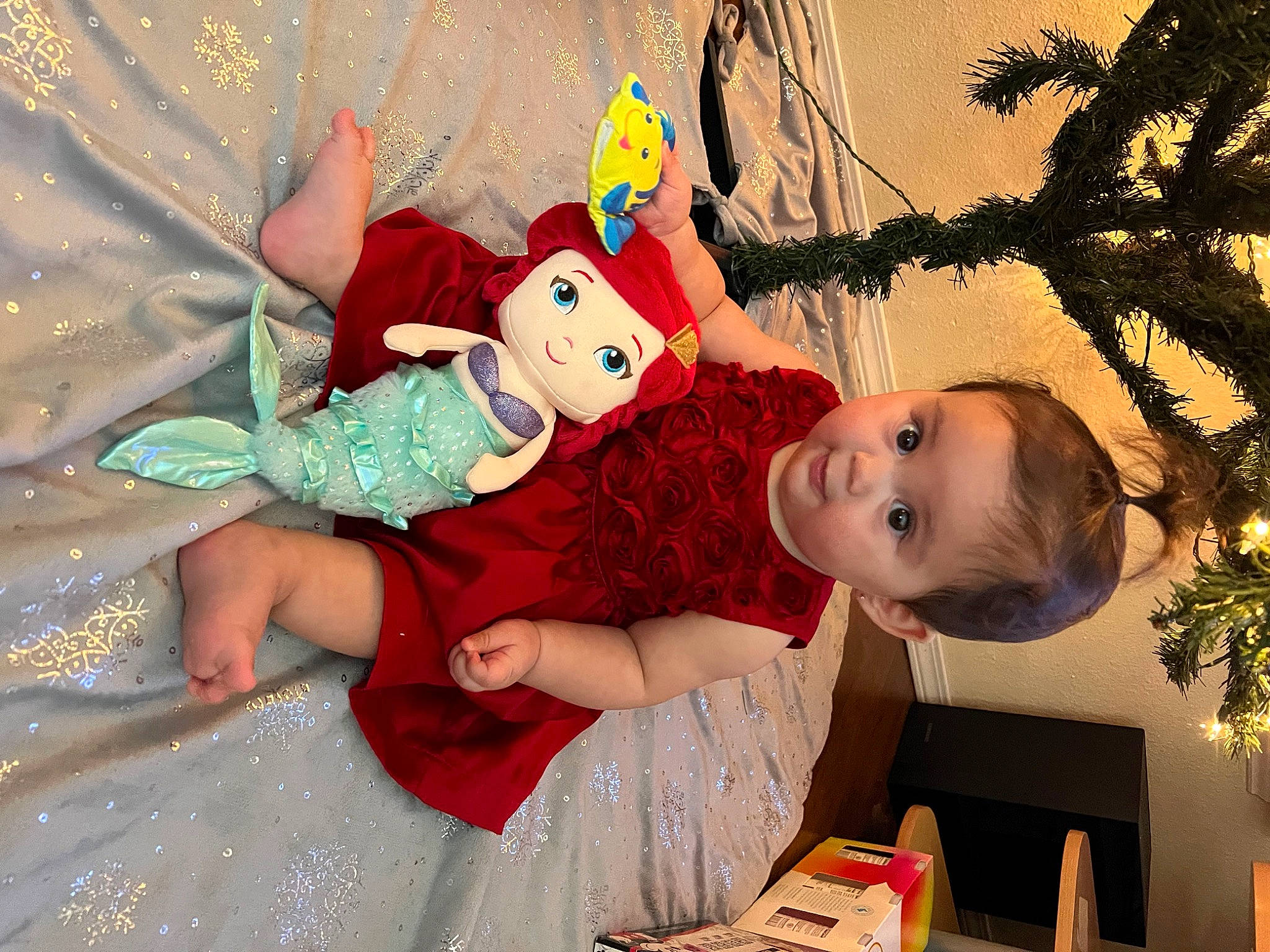 Anela is registered to the contest to win money with this photo: baby, baby_toddler_clothing, child, christmas, christmas_eve, christmas_ornament, doll, event, facial_expression, fictional_character, fun, happy, holiday, ornament, party_supply, pattern, person, playing_with_kids, smile, toddler