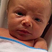 Kaysen Shane is registered to the contest to win money with this photo: baby, newborn, face, skin, towel, blue_edge, wrapped, closeup, water_droplets, bath, infant, child, expression, serious, lying_down, head, eyes, nose, mouth, skin_texture