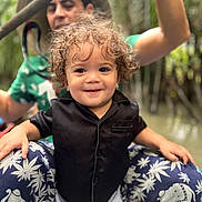 Soan a rejoint le concours — aidez-le/la à gagner de superbes lots ! toddler, child, curly_hair, black_shirt, smiling, person, adult, hat, pants, elephant_pattern, outdoor, nature, greenery, portrait, happy, sitting, summer, casual_clothing, family, playful
