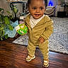 ball, carpet, child, cute, decor, happy, home, indoor, joy_sign, living_room, natural_light, plant, shoes, smiling, standing, toddler, toy, tracksuit, window, wood_floor