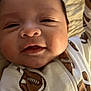 Greyson is registered to the contest to win money with this photo: baby, infant, face, smile, onesie, football_pattern, closeup, child, cute, sleepwear, blanket, soft_lighting, happy, young, skin, portrait, newborn, person, head, lying_down