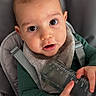 baby, bib, big_eyes, bottle, child, close_up, curious_expression, drool, eyes, face, fine_hair, green_clothing, hands, high_chair, indoor, infant, portrait, safety_strap, skin, soft_lighting