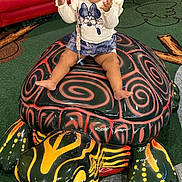Christina is registered to the contest to win money with this photo: animal_ride, barefoot, carpet, child, colorful, dress, happy, headband, indoor, joy, padded_seating, play_area, playful, portrait, sitting, skirt, smiling, toddler, turtle, turtle_statue