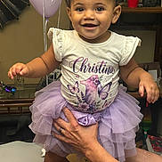Christina is registered to the contest to win money with this photo: toddler, child, smiling, portrait, tiara, dress, tutu, lavender, butterflies, birthday, balloons, indoor, celebration, sitting, being_held, adult_hands, family, happy, furniture, home