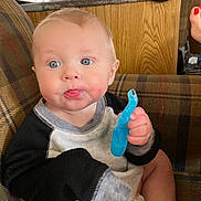 Kaliber joined the competition — help win amazing prizes! baby, child, blue_eyes, teething_toy, drool, plaid_couch, indoor, casual_clothing, light_hair, curious_expression, diaper, hand, face, person, infant, home, soft_lighting, seated, cute, comfort