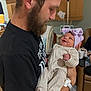 man, baby, newborn, hospital, beard, smile, holding, bow_hat, medical_equipment, bed, black_shirt, infant, portrait, indoor, care, family, love, person, clothing, warmth