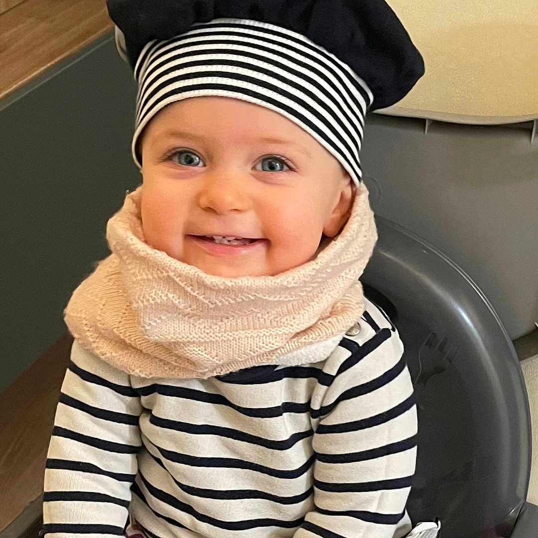 Elena a rejoint le concours — aidez-le/la à gagner de superbes lots ! baby, babylaughing, baseballcap, bodypart, cap, clothing, coat, face, happy, hat, head, jacket, mouth, person, photography, portrait, scarf, sitting, smile, teeth
