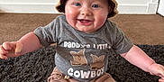 Kaijay joined the competition — help win amazing prizes! baby, child, smiling, hat, crocheted_hat, cowboy, shirt, text_on_shirt, sitting, indoor, rug, carpet, happy, cute, chubby, blue_eyes, shorts, skin, person, infant