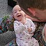 baby, adult, child, onesie, pajamas, comic_pattern, carpet, floor, smile, joy, cuddle, cute, interaction, indoor, person, happy, face, hand, head, playful