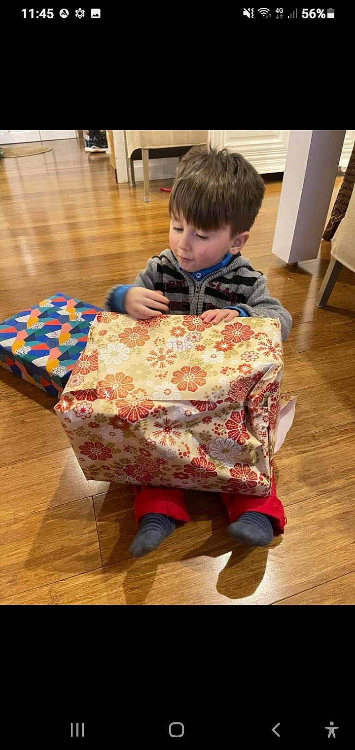 Mylan participe au concours pour gagner de l'argent avec cette photo : chair, child, christmas, event, flooring, fun, gift_wrapping, hardwood, head, holiday, leisure, linens, pattern, person, present, room, sitting, sleeve, toddler, wood