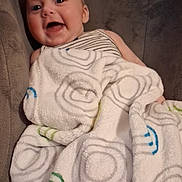 Harmony joined the competition — help win amazing prizes! baby, blanket, child, comfort, couch, cozy, cute, face, happy, indoor, infant, patterned_blanket, portrait, relaxing, seated, smile, soft_texture, striped_clothing, wrapped, young_child