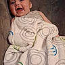 baby, blanket, child, comfort, couch, cozy, cute, face, happy, indoor, infant, patterned_blanket, portrait, relaxing, seated, smile, soft_texture, striped_clothing, wrapped, young_child