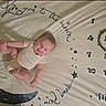 baby, blanket, calendar, child, clothing, cute, decorative, face, happy, indoor, infant, joyful, lying_down, months, moon, playful, skin, smiling, soft, stars