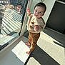 toddler, child, barefoot, indoor, sunlight, reflection, glass, window, door, carpet, sweater, pants, standing, curious, baby, person, young_child, casual_clothing, home, daylight