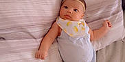 Oni is registered to the contest to win money with this photo: baby, infant, bed, pillow, clothing, headband, bib, socks, bow, person, cute, lying_down, indoor, soft_fabric, sleepwear, child, newborn, resting, portrait, comfortable