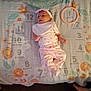 Oni is registered to the contest to win money with this photo: baby, infant, milestone_blanket, pajamas, headband, bib, floor, feet, slippers, flower_pattern, months, circle_marker, person, lying_down, home, wood_floor, pink_clothing, cute, child, indoors