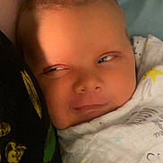 Carter joined the competition — help win amazing prizes! baby, infant, blanket, swaddle, face, expression, eyes, skin, head, closeup, cozy, cute, child, newborn, indoors, soft_lighting, calm, resting, person, sleepwear